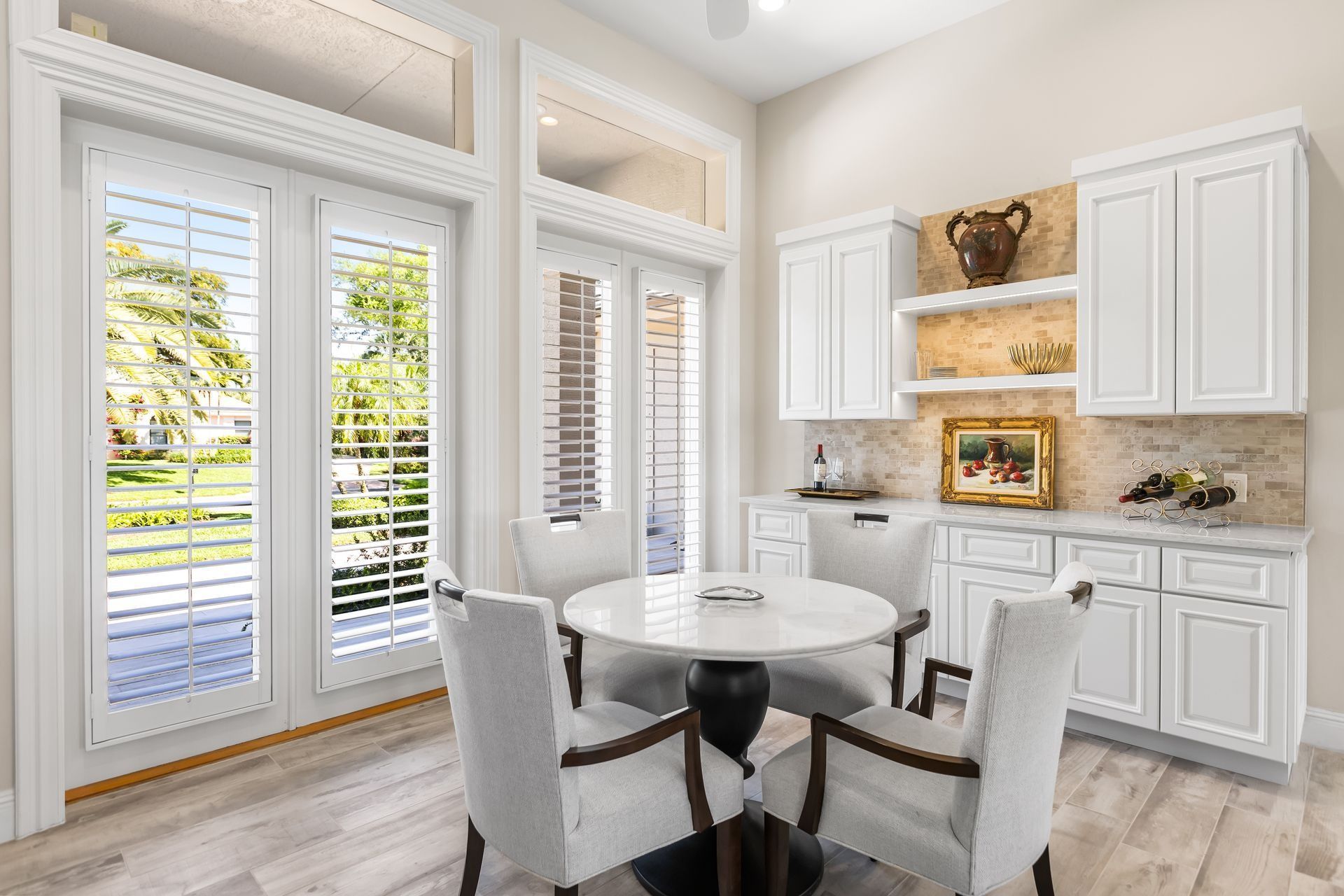 Dining area with a round table, white cabinets, and French doors leading to a yard.
