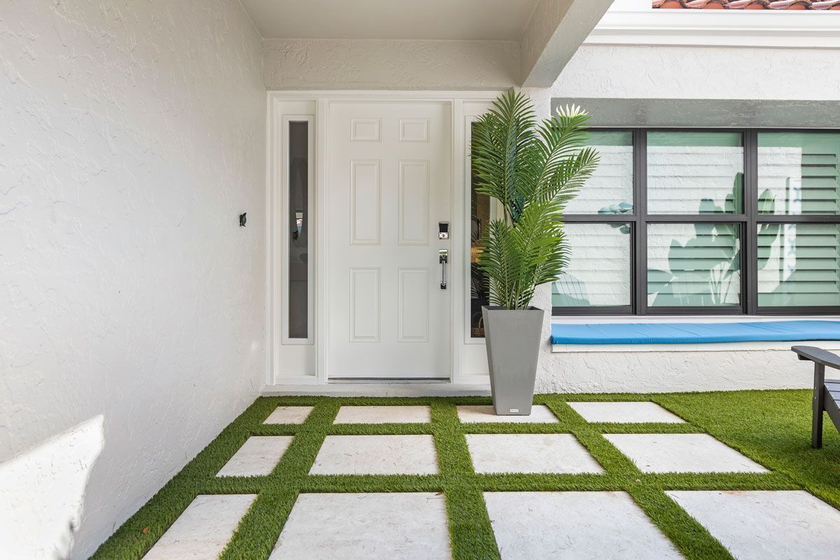 White front door with rectangular pavers and greenery.