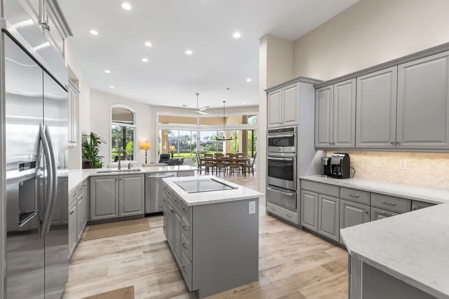 Modern kitchen with gray cabinets, island, and appliances. Light wood floors, and view of dining area.