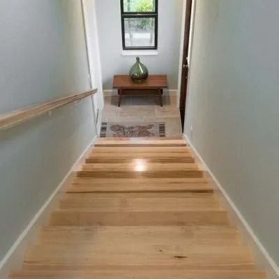 Wooden staircase leading down with gray walls, small table, and a window at the bottom.
