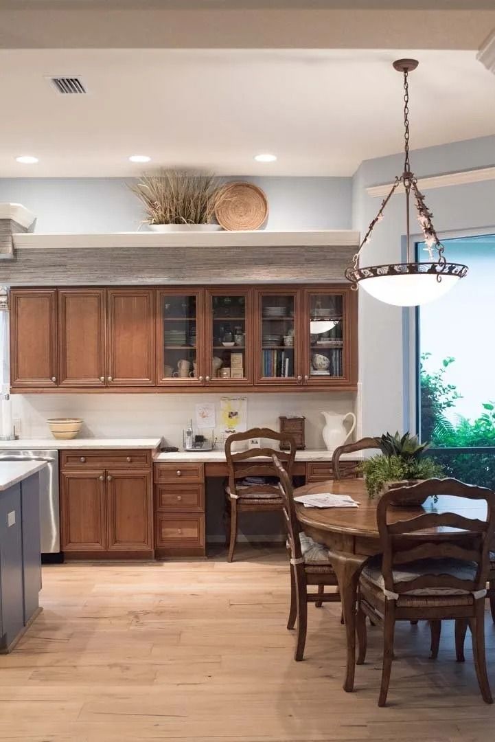 Kitchen with wooden cabinets, dining table, and light wood flooring.