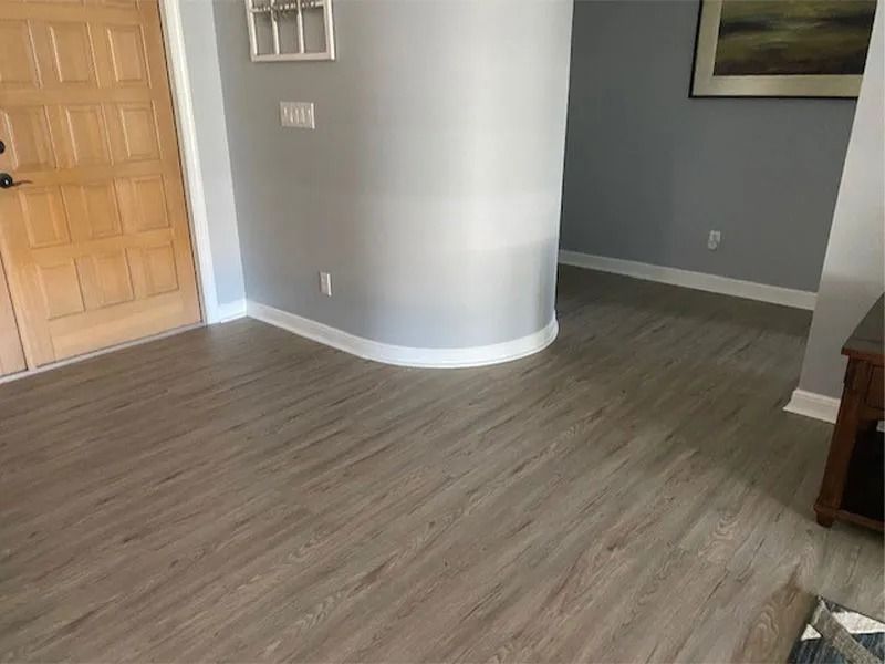 Entryway with light wood-look flooring, light gray walls, white trim, and a wooden door.