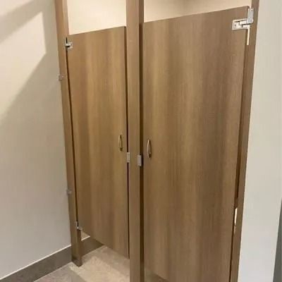 Two light brown restroom stalls with closed doors, side by side.