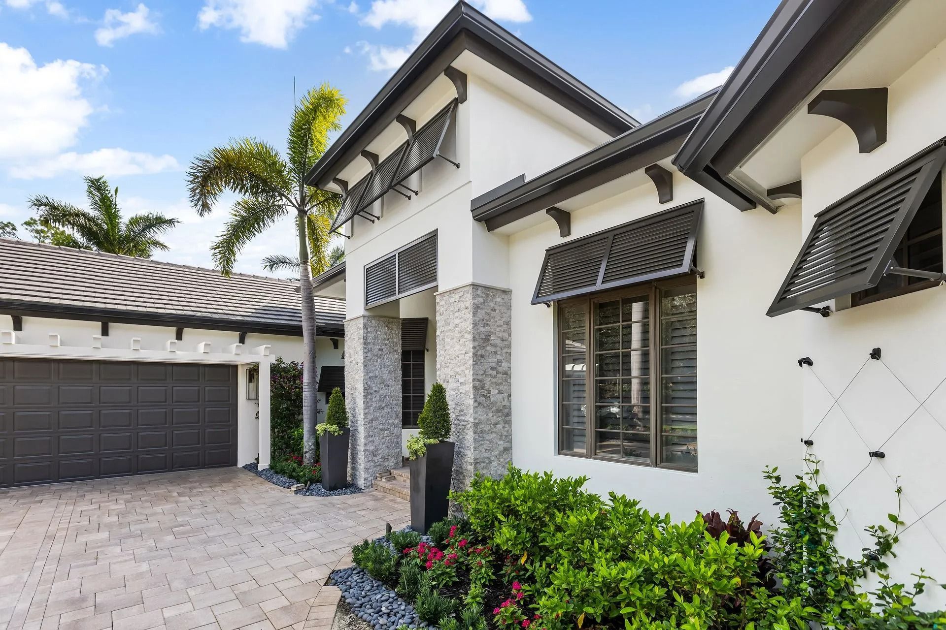 White and dark gray modern house exterior with shutters and driveway.