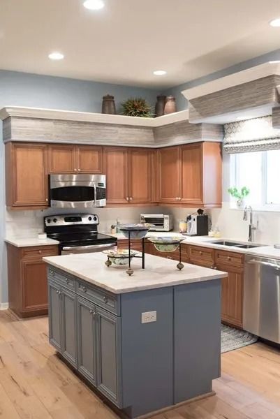 Kitchen with brown cabinets, blue island, stainless steel appliances, and wood flooring.