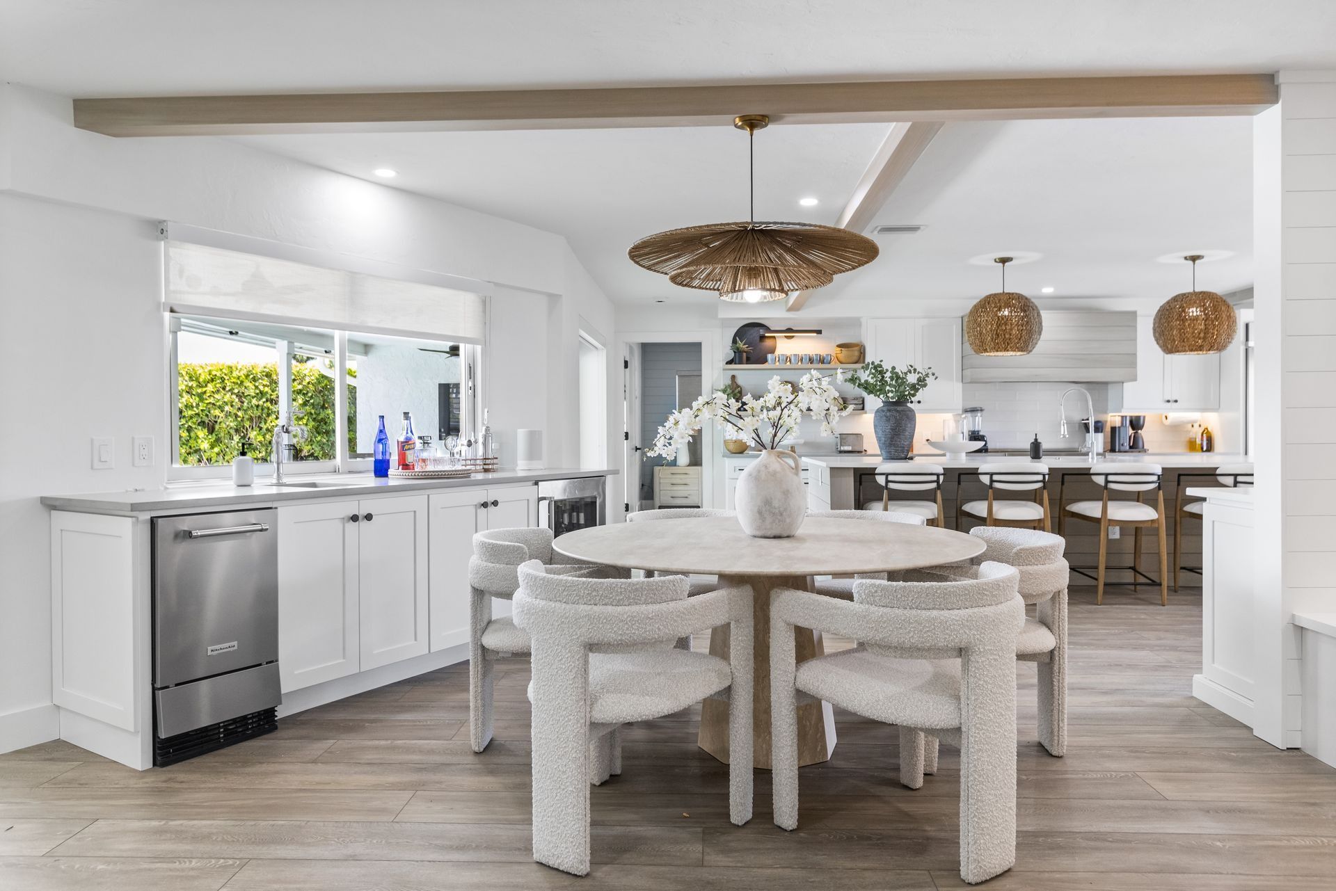 Bright kitchen with white cabinets, a round table with fluffy chairs, and a chandelier.