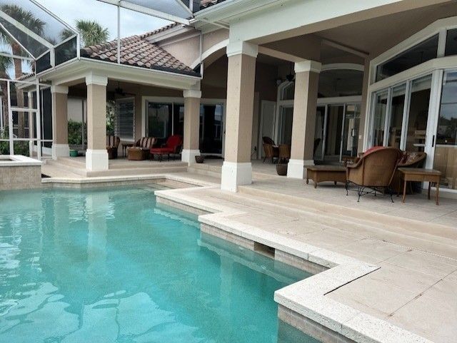 Pool and patio of a home with columns, pool, and lounge furniture.