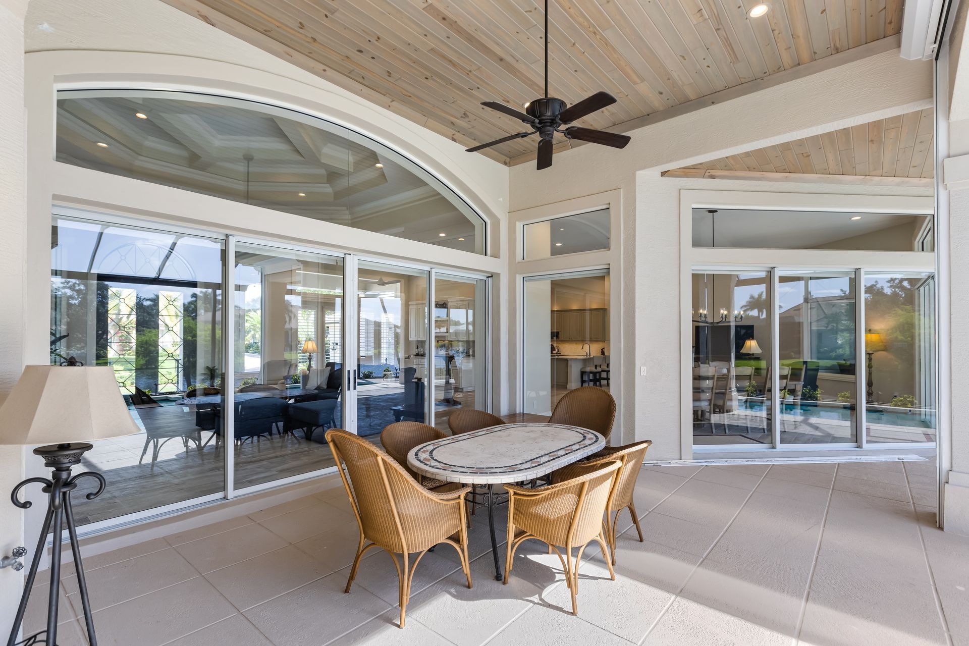 Patio with table, chairs, sliding glass doors, and ceiling fan. Light beige walls and wood ceiling.