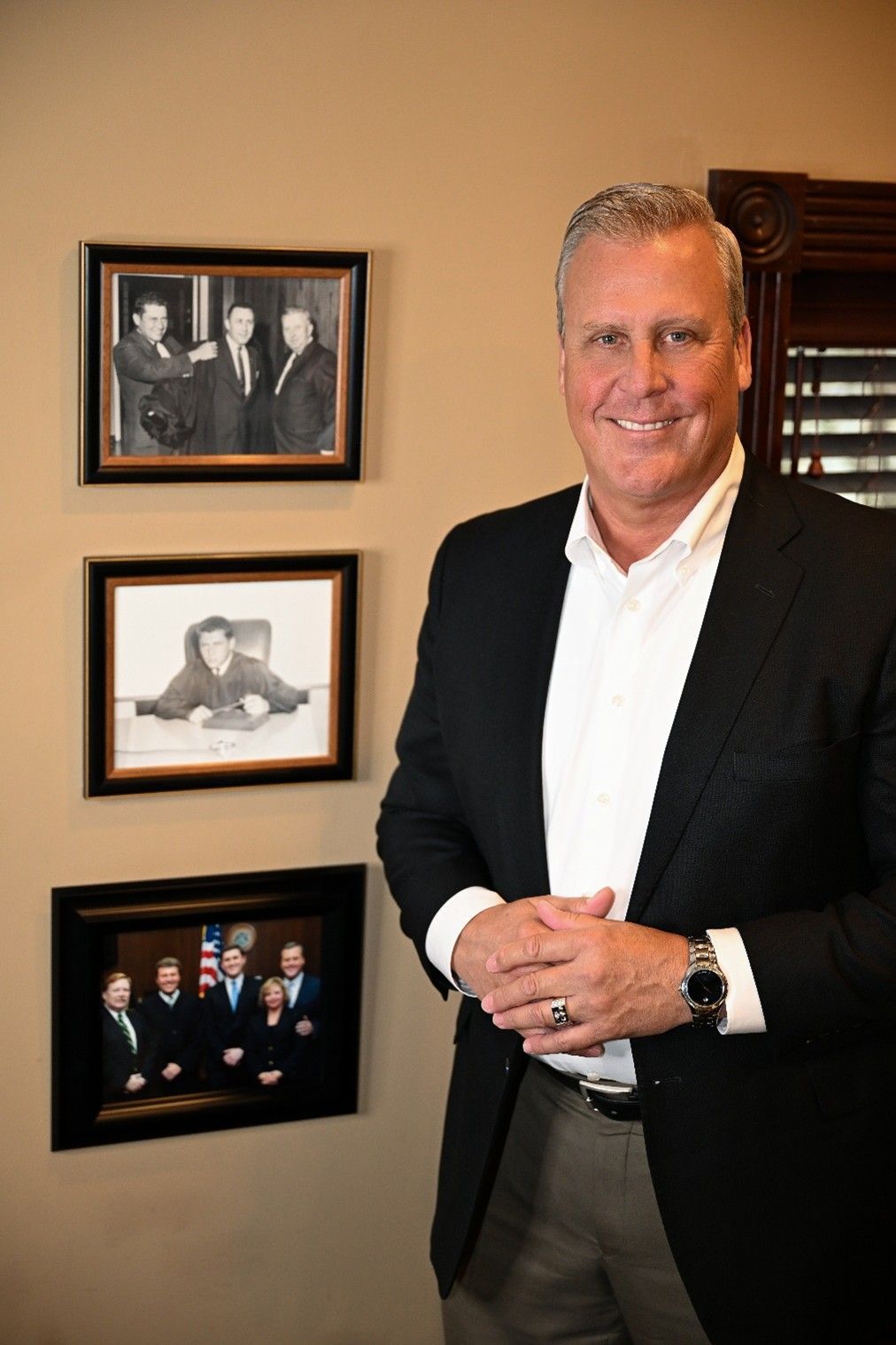 A professional sitting at a desk in an office, smiling while looking at the camera with open books and a pen.