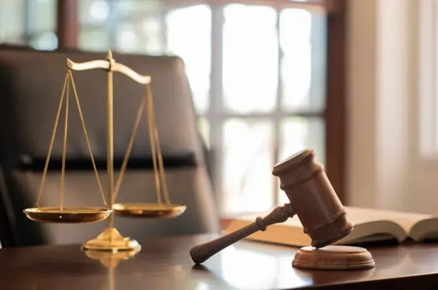 Scales of justice and gavel on a desk in a law office, representing legal proceedings.
