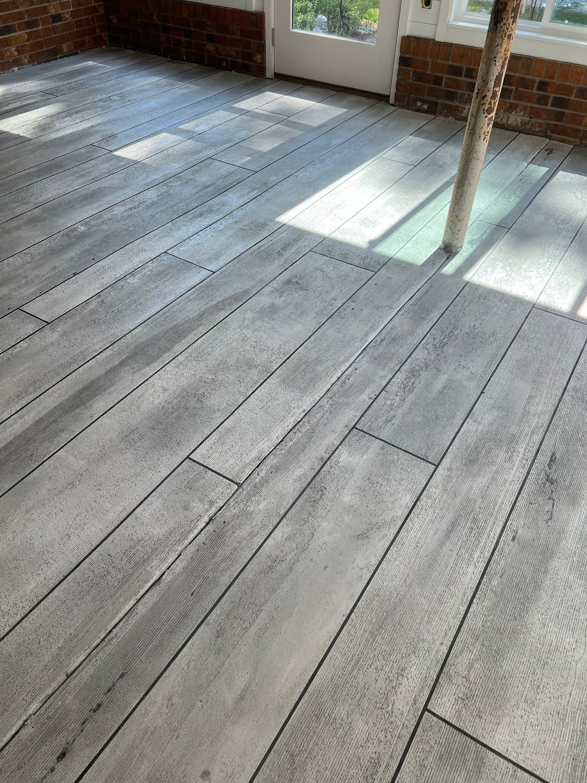 A room with a wooden floor and a brick wall.