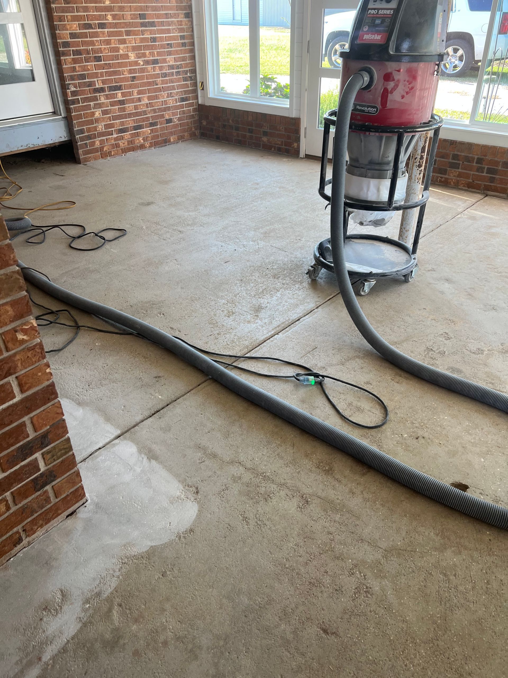 A vacuum cleaner is sitting on a concrete floor in a room.
