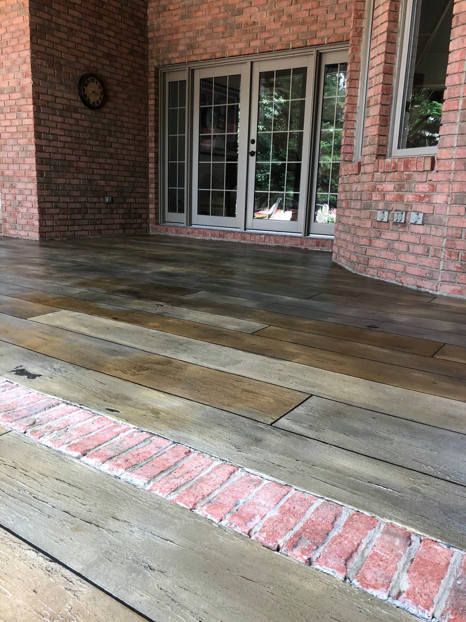 A patio with a brick wall and sliding glass doors.