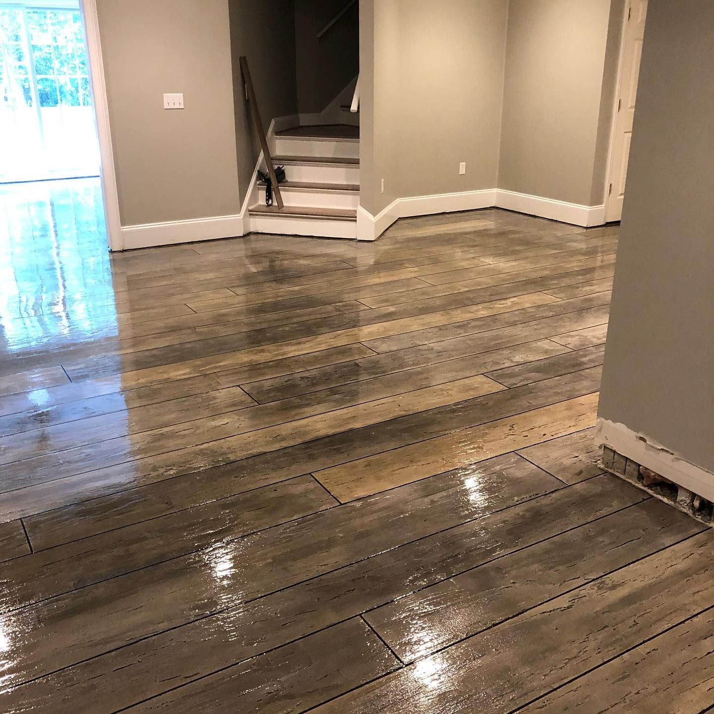 A room with a wooden floor and stairs in the background.