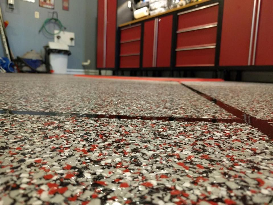 A close up of a garage floor with red cabinets