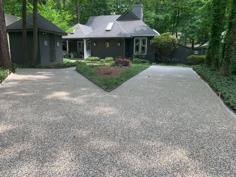 A gravel driveway leading to a house in the woods