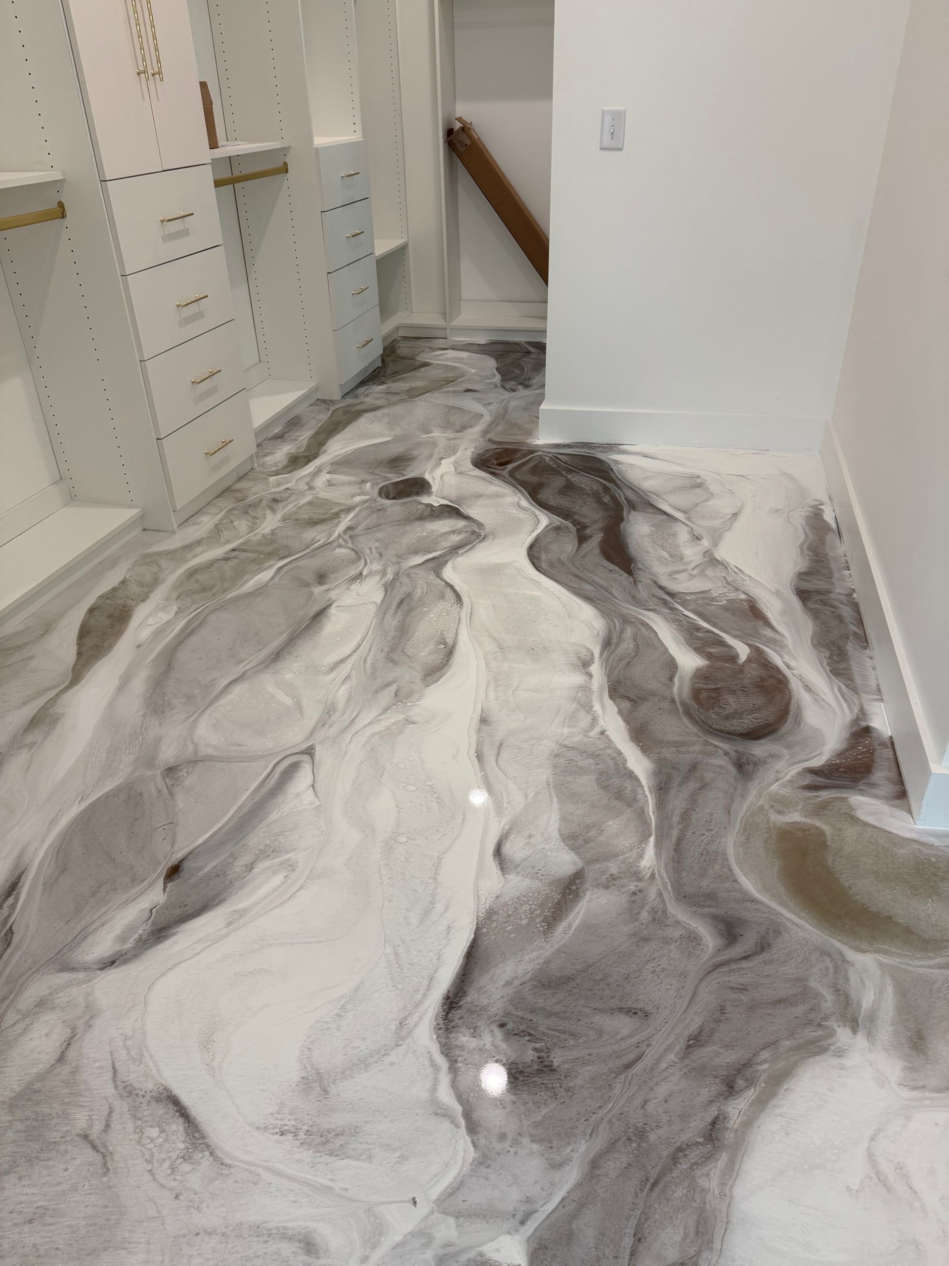 A marble floor in a closet with a staircase in the background.
