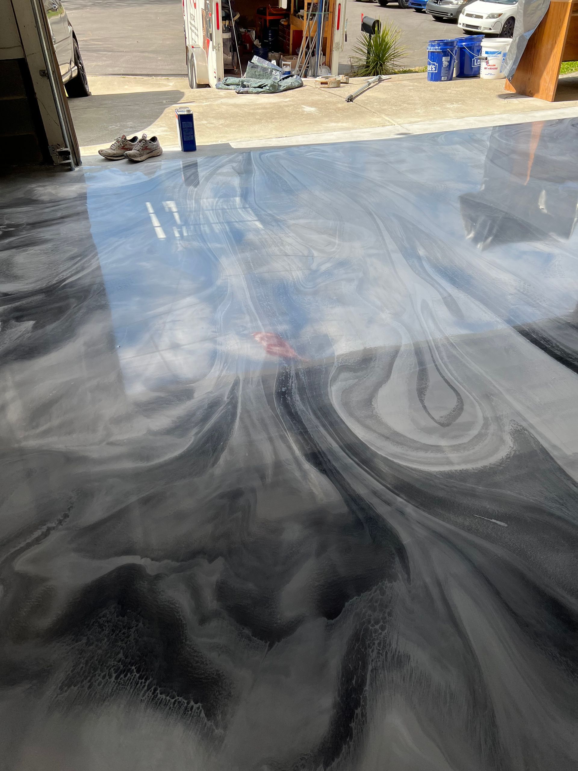 A gray and white marble floor is being painted in a garage.