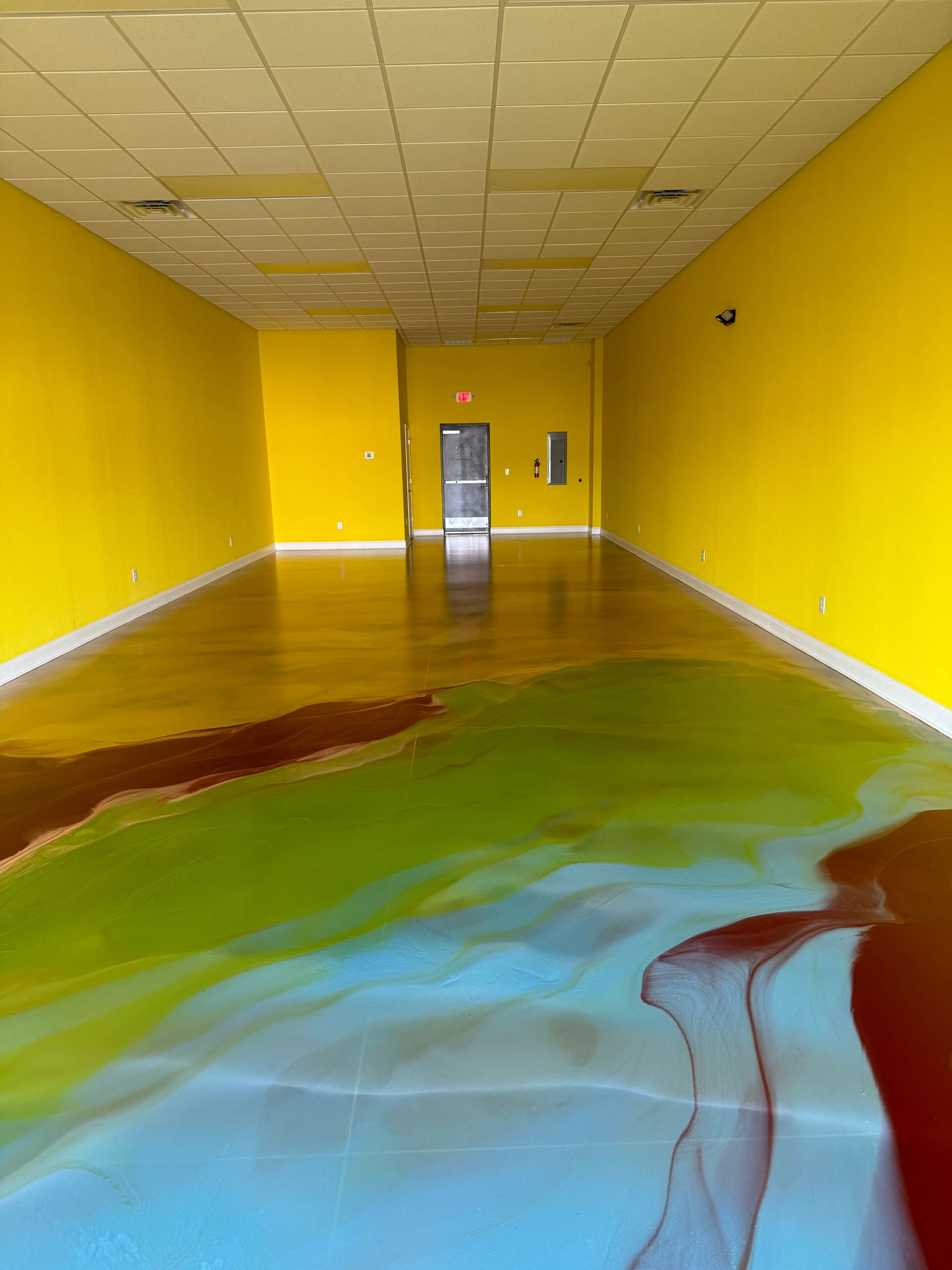 An empty room with yellow walls and a colorful floor