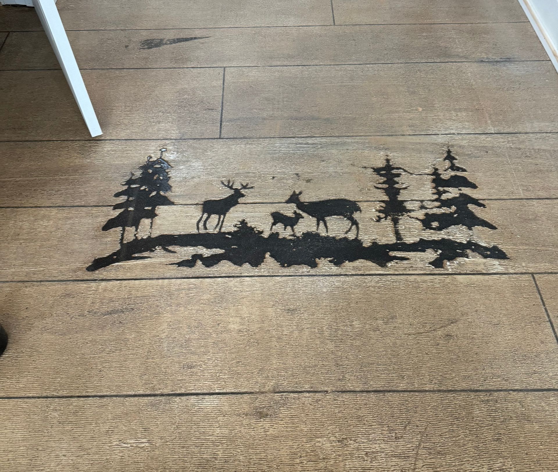 A wooden floor with a silhouette of deer and trees on it