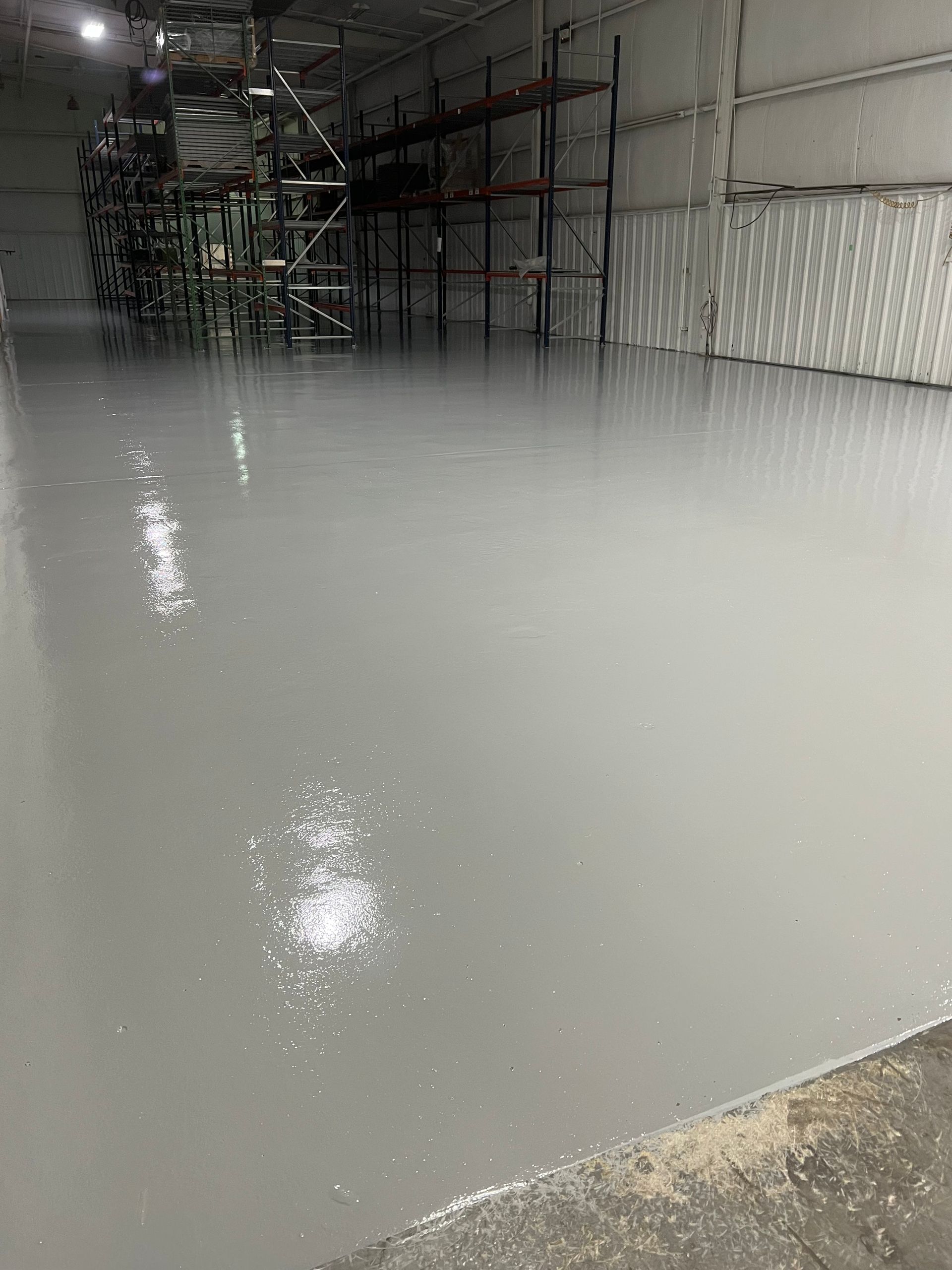 A large warehouse with a concrete floor and a lot of shelves.