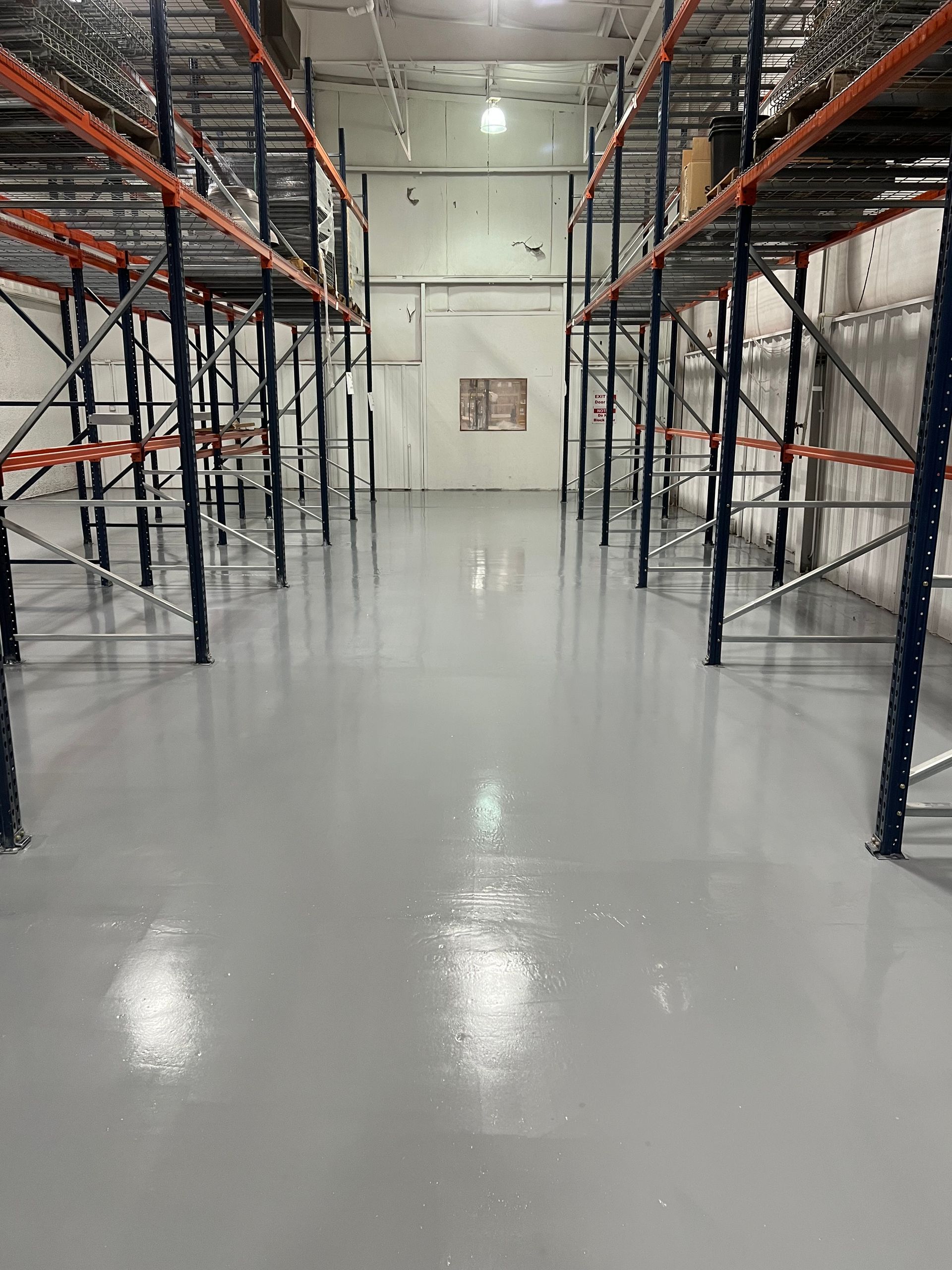 A large warehouse with lots of shelves and a gray floor.