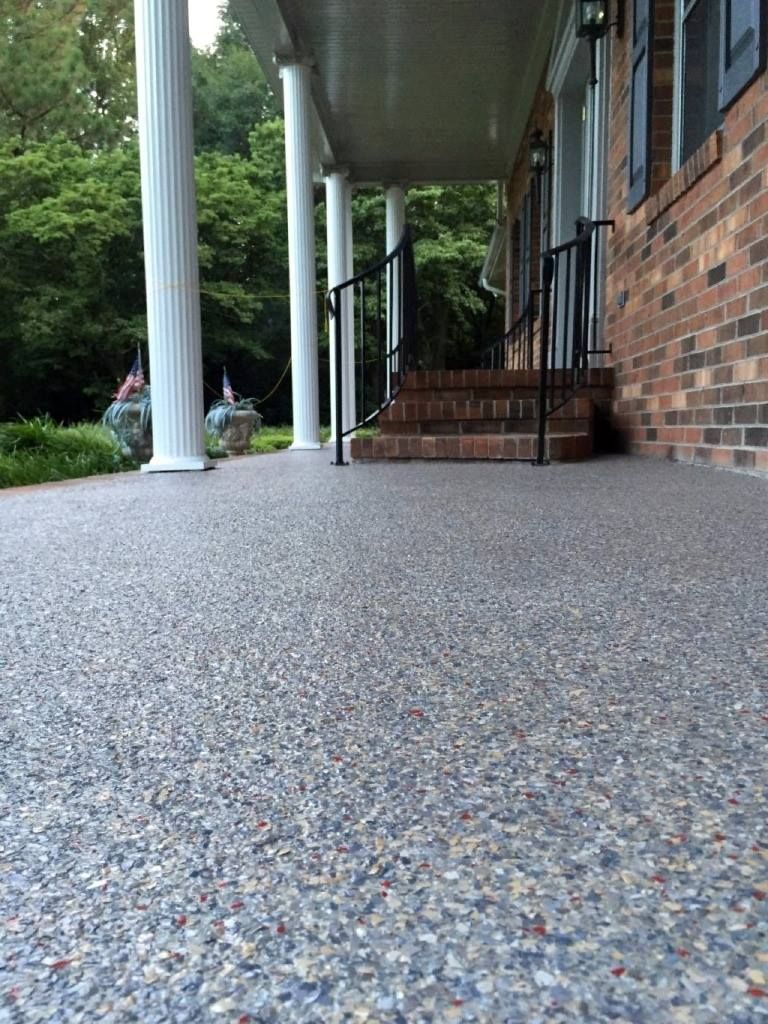 A brick house with a porch and stairs with a gravel floor.