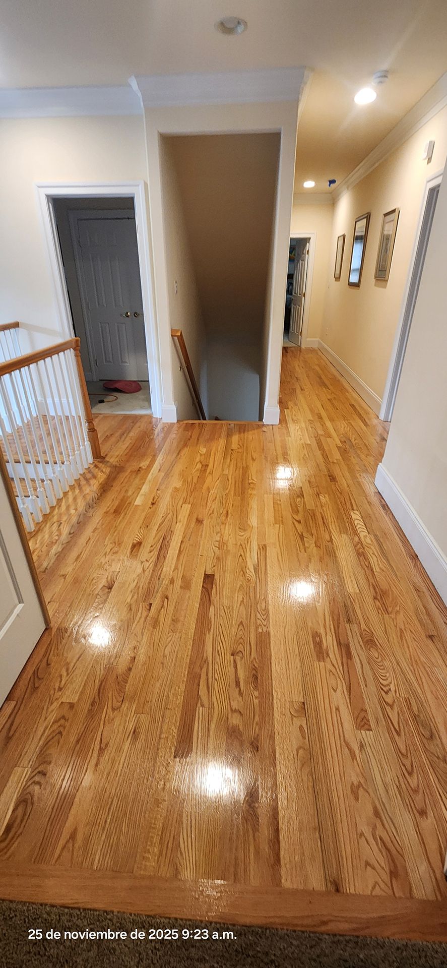 hallway with hardwood floors, a staircase, and several doors, lit by overhead lights