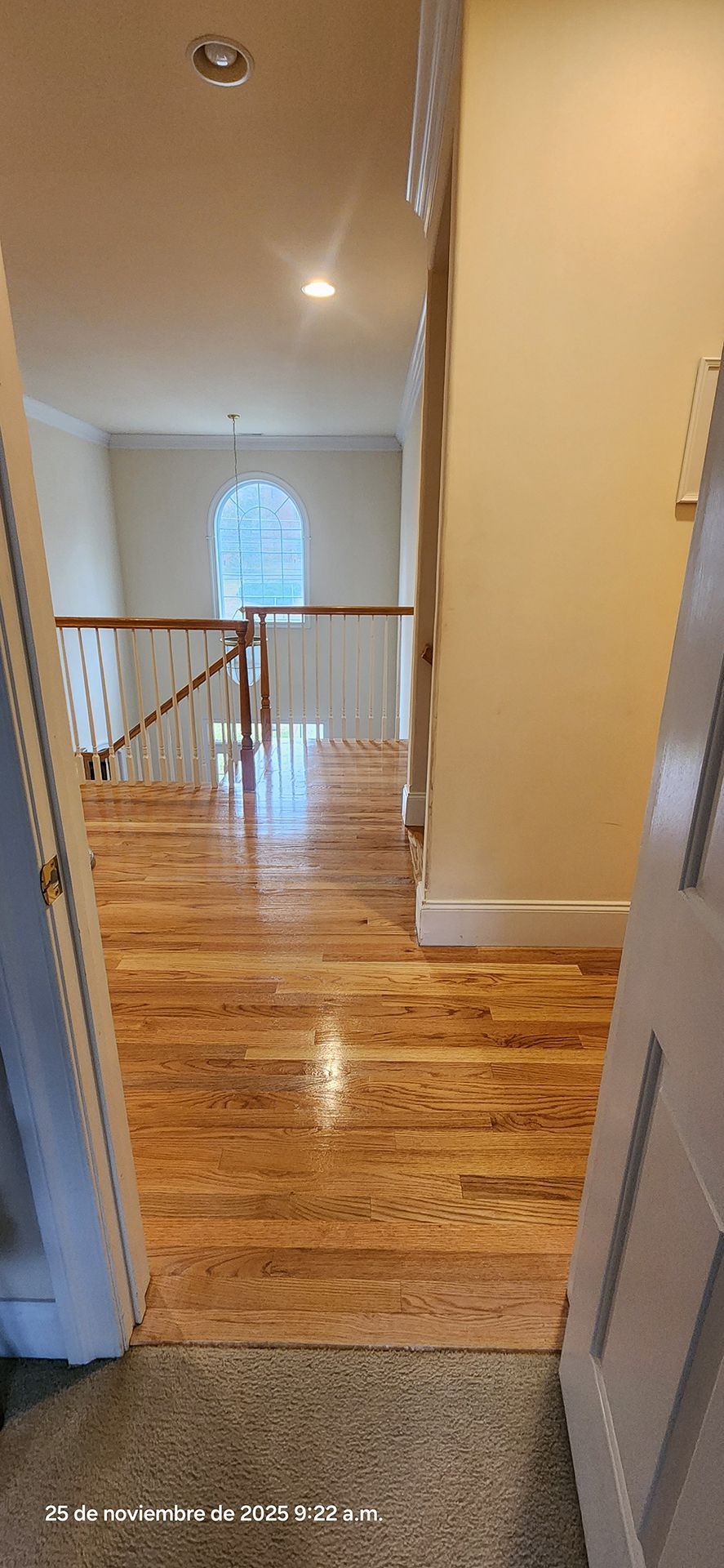 hallway with hardwood floor leading to a window and staircase