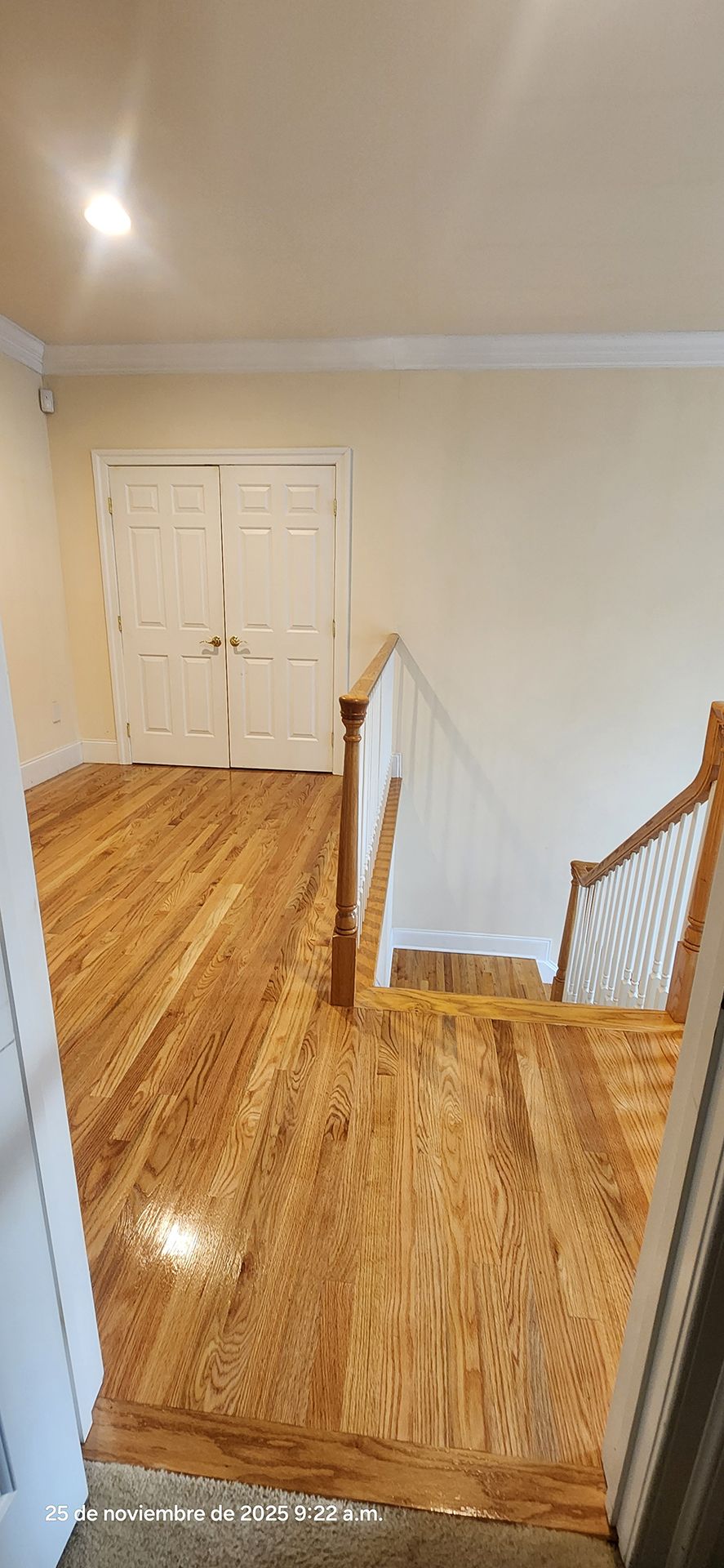 entryway with wooden floors, staircase, white railing, and double doors