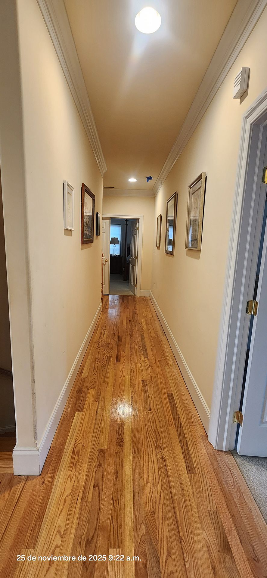 long hallway with hardwood floors, walls with framed artwork