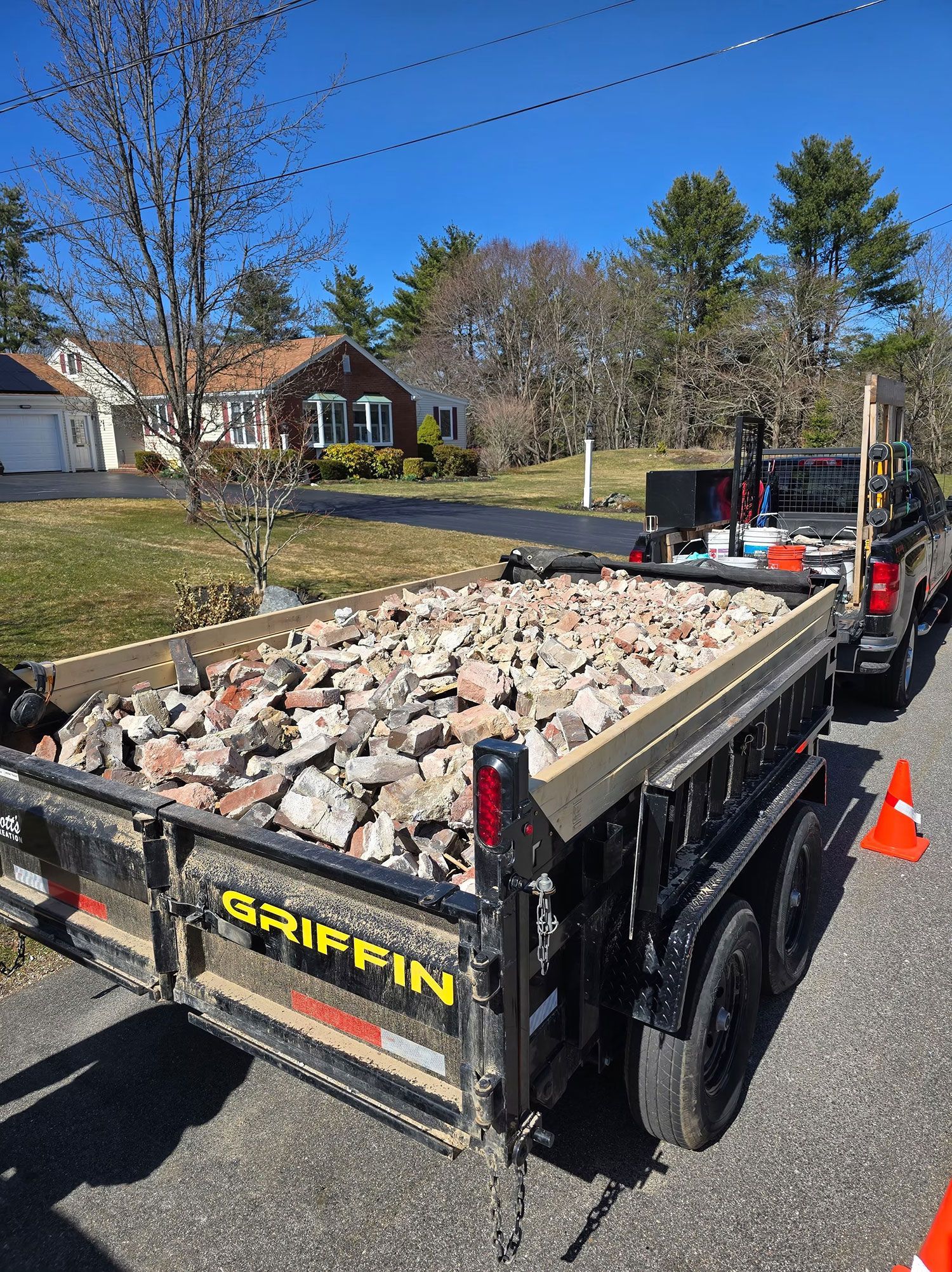 Dump trailer filled with broken concrete on a sunny residential street