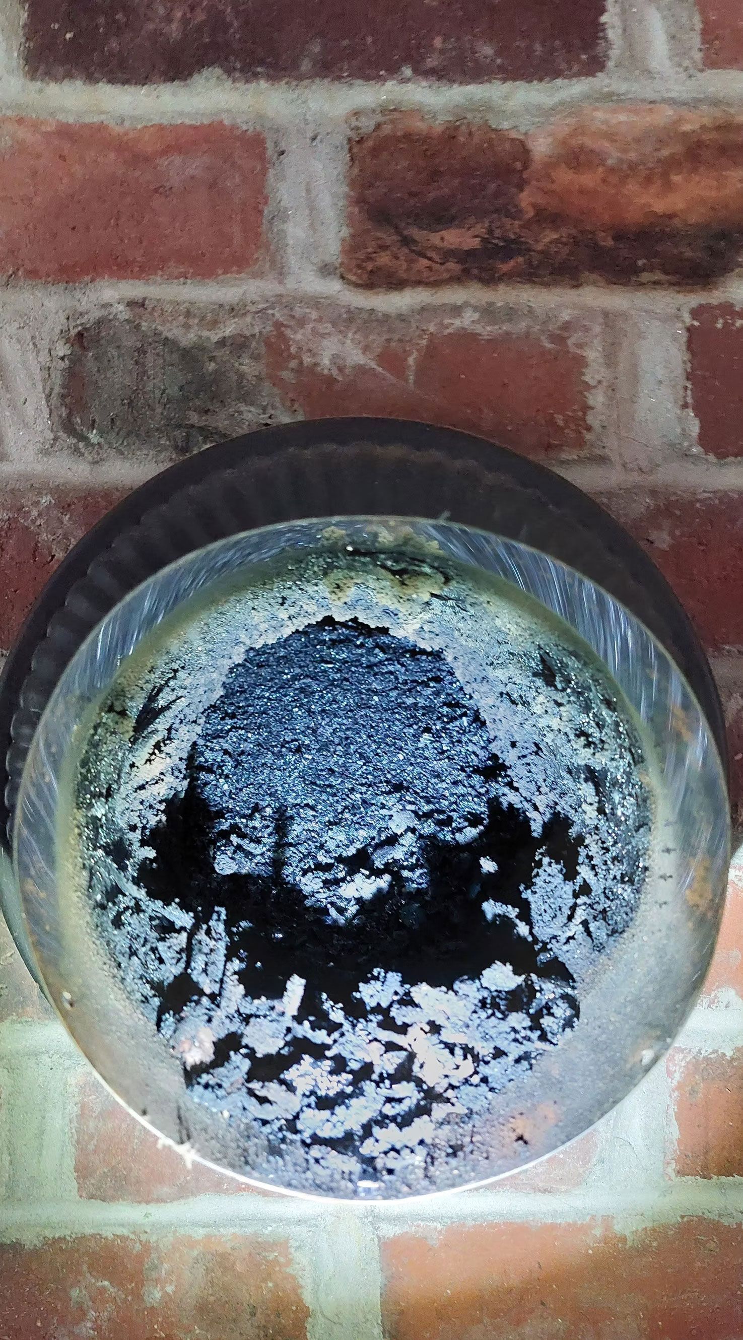 Round outdoor light with dark center on a red brick wall