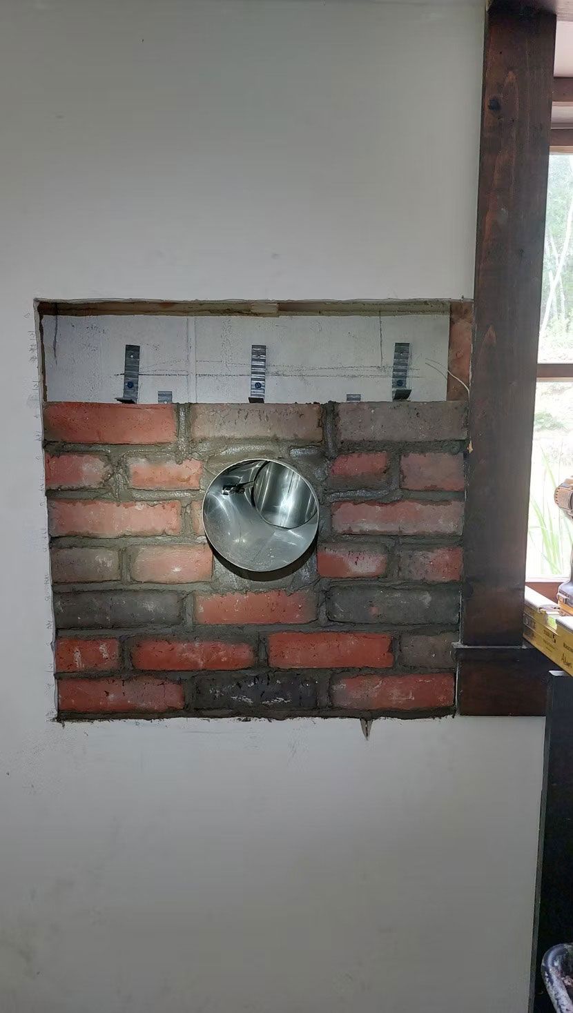 Brick wall niche with a round metal vent or light fixture set into it