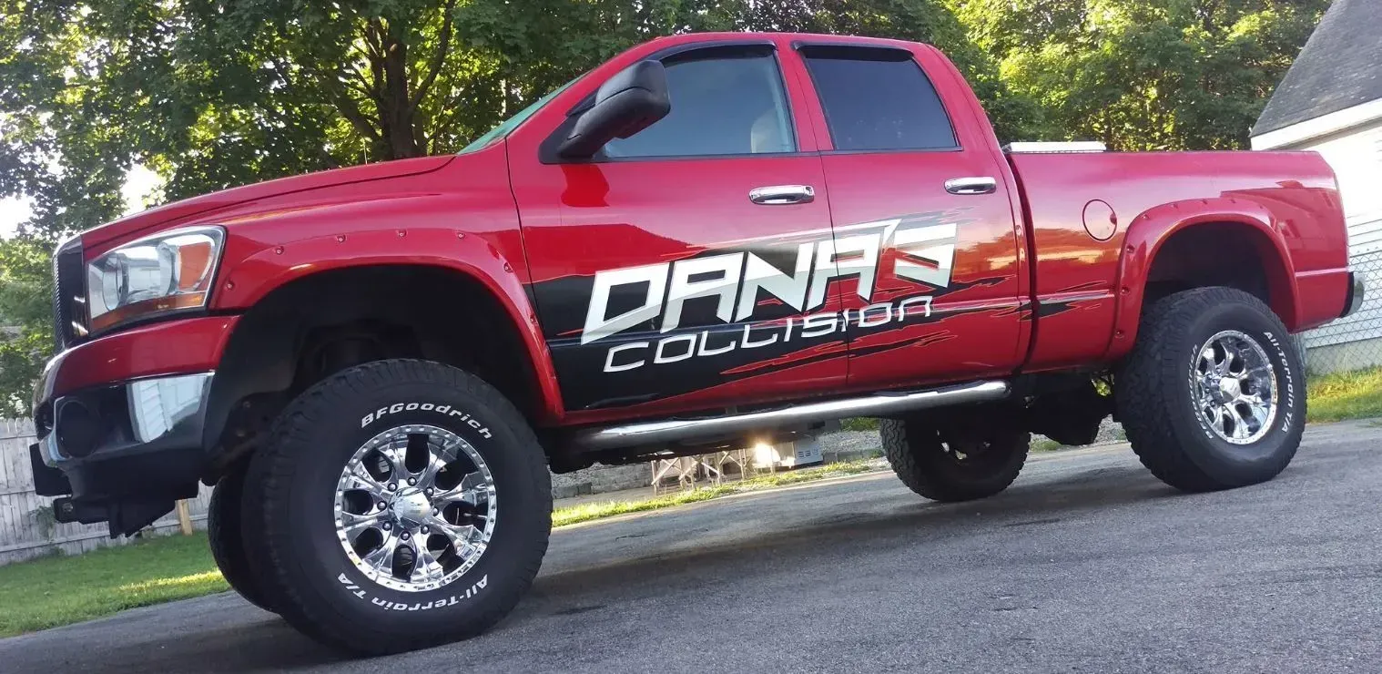 Red pickup truck with DANK Collision logo parked outdoors on a sloped road