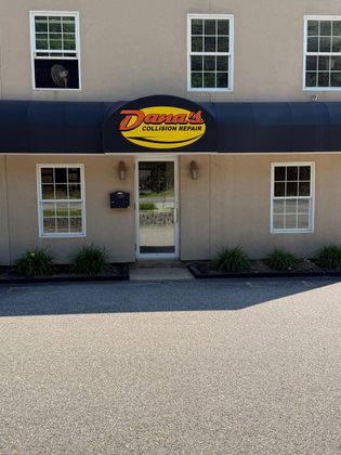 Tan building with a yellow-and-red business sign above a glass door and windows.