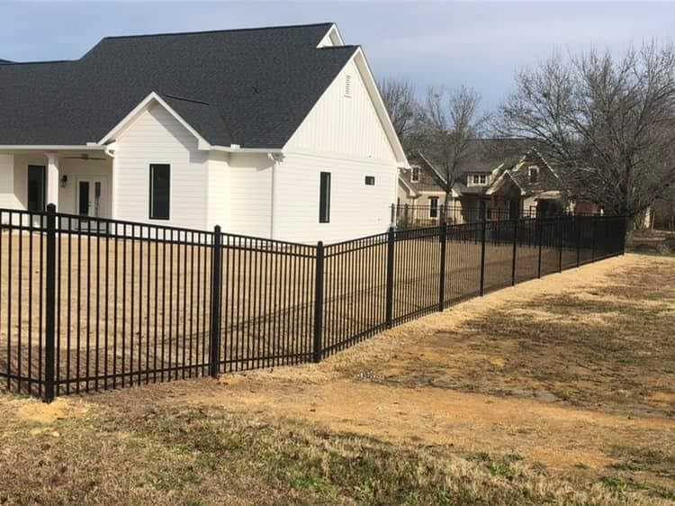 A white house with a black fence in front of it.