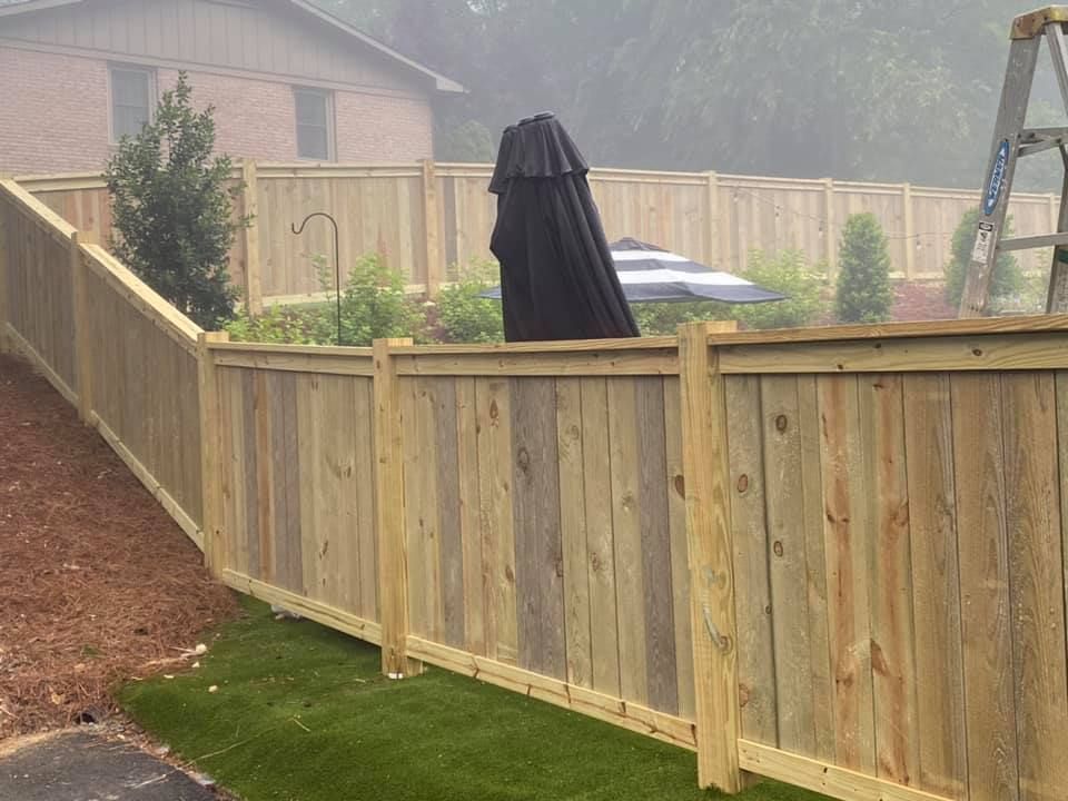 A wooden fence with a black umbrella behind it.