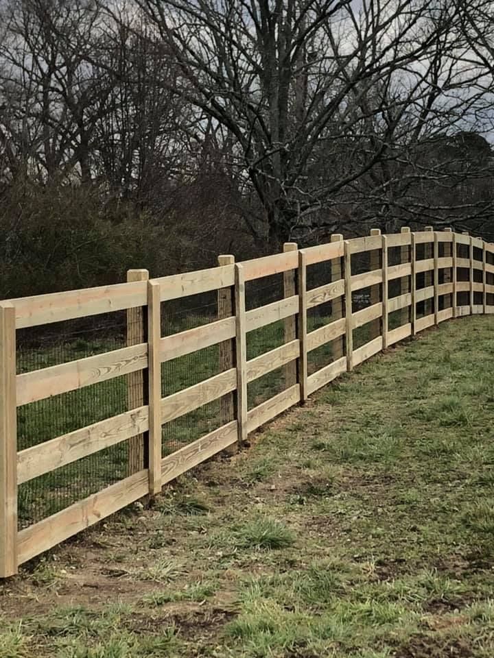 A wooden fence is sitting in the middle of a grassy field.