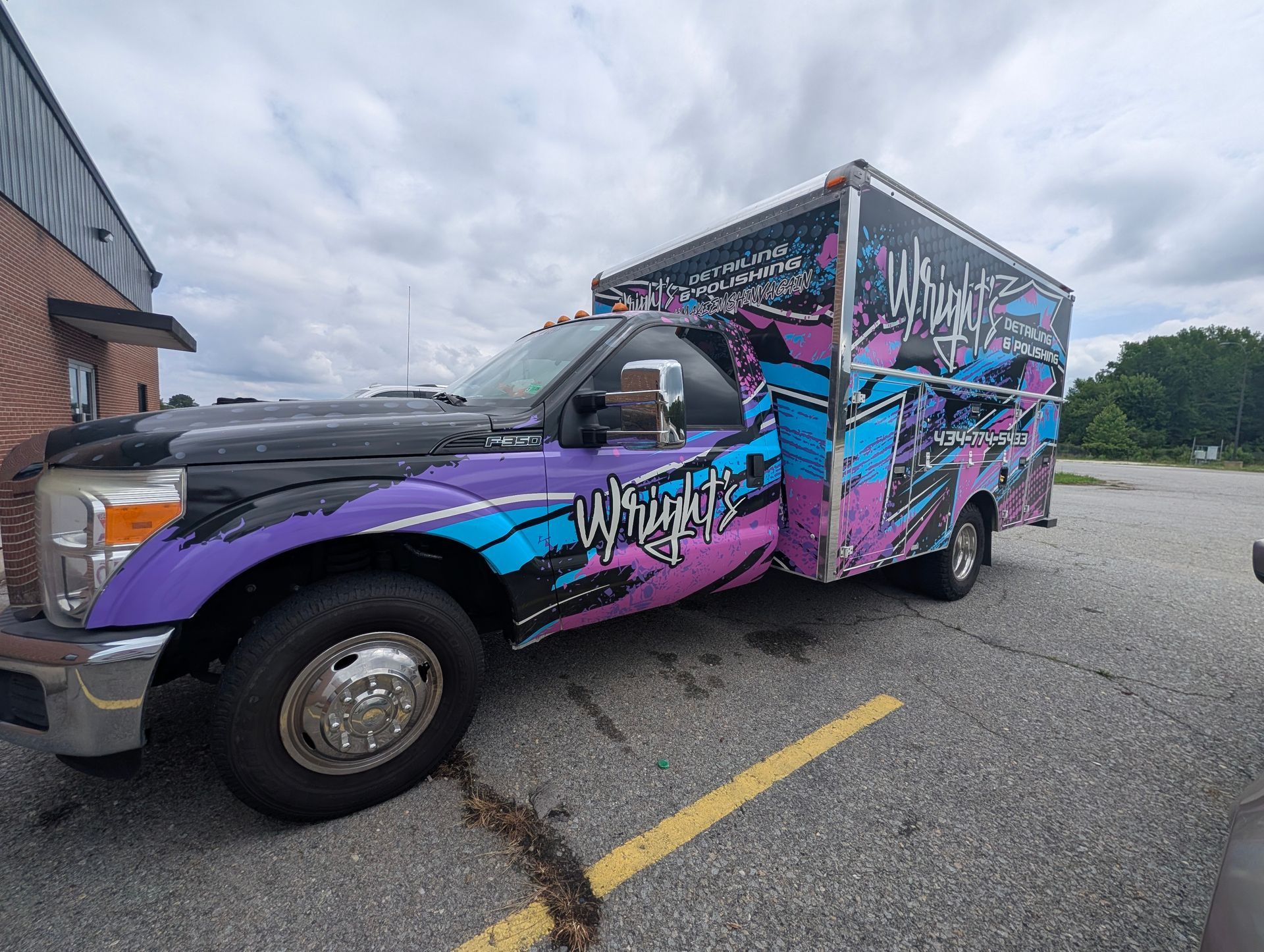 Graffiti-wrapped purple and blue box truck parked in a lot under cloudy skies