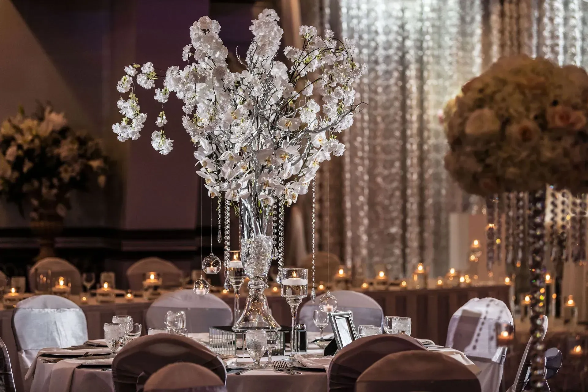 Elegant banquet hall with crystal floral centerpieces, white linens, and soft candlelit decor