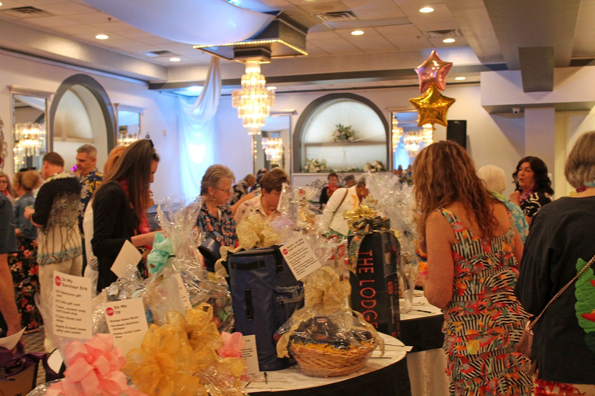 People browsing a colorful jewelry display at a crowded indoor market or boutique event