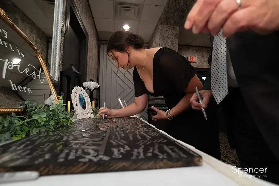 Woman leans over a decorated display table indoors while someone points nearby, at a candlelit event