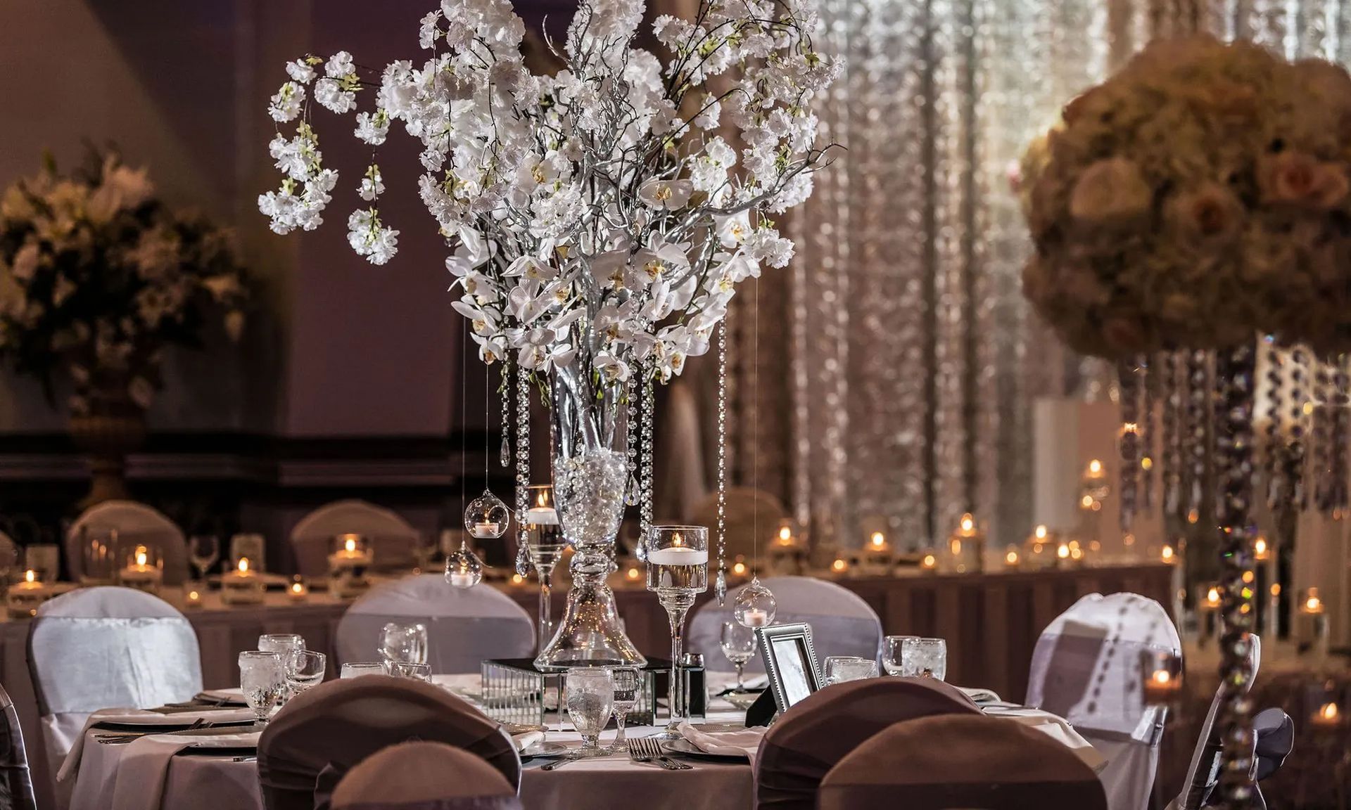 Elegant banquet hall with crystal centerpieces, candlelight, and round tables set for an event