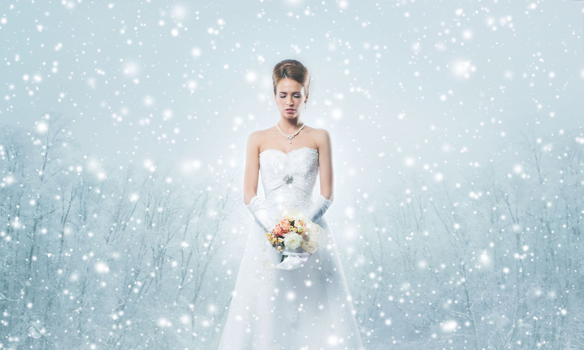 Bride in a white wedding dress holding a bouquet, standing in falling snow against a pale blue background