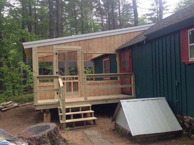 A small house with a screened in porch and stairs
