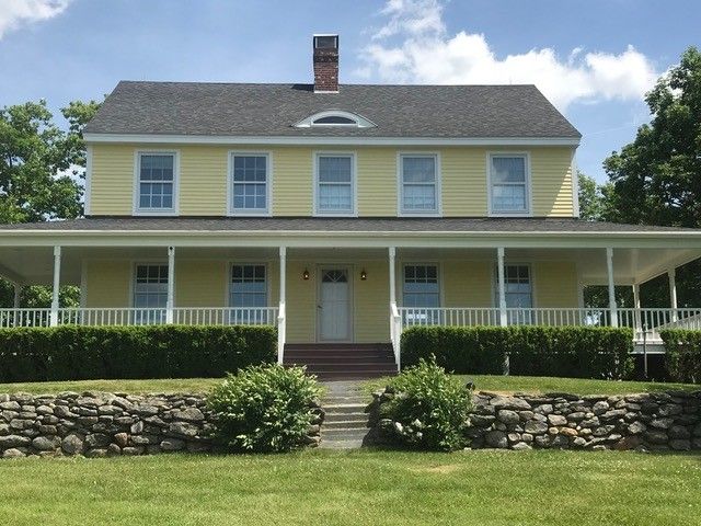 A large yellow house with a large porch