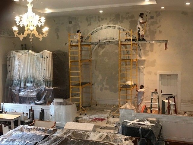 A group of people are painting a wall in a room.