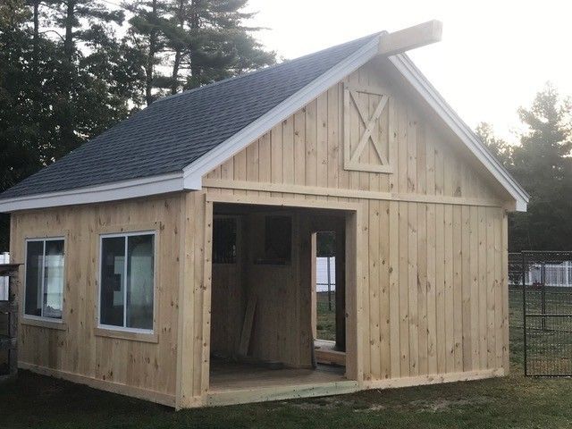 A small wooden house with a roof that has a x on it