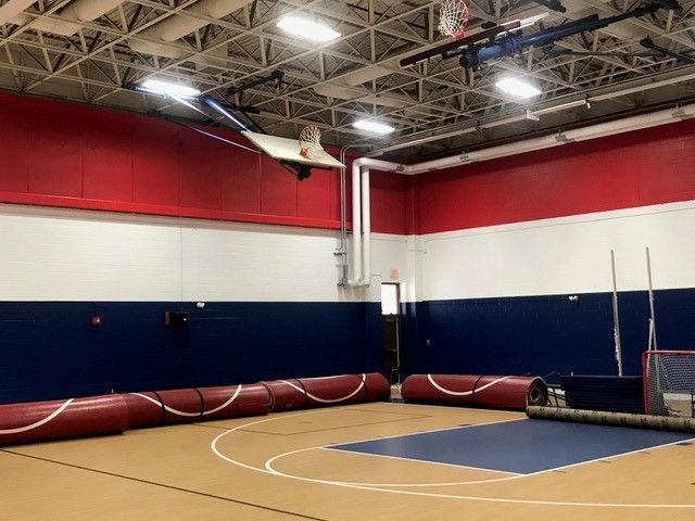 A basketball court in a gym with red, white and blue walls.